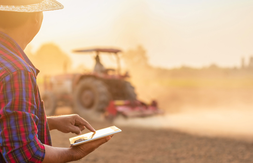 Agricultor revisando actividad de tractor y registrándola en la tablet